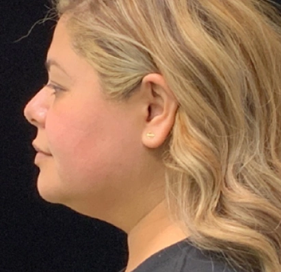 Side profile portrait of a woman with wavy blonde hair and stud earring against a black background